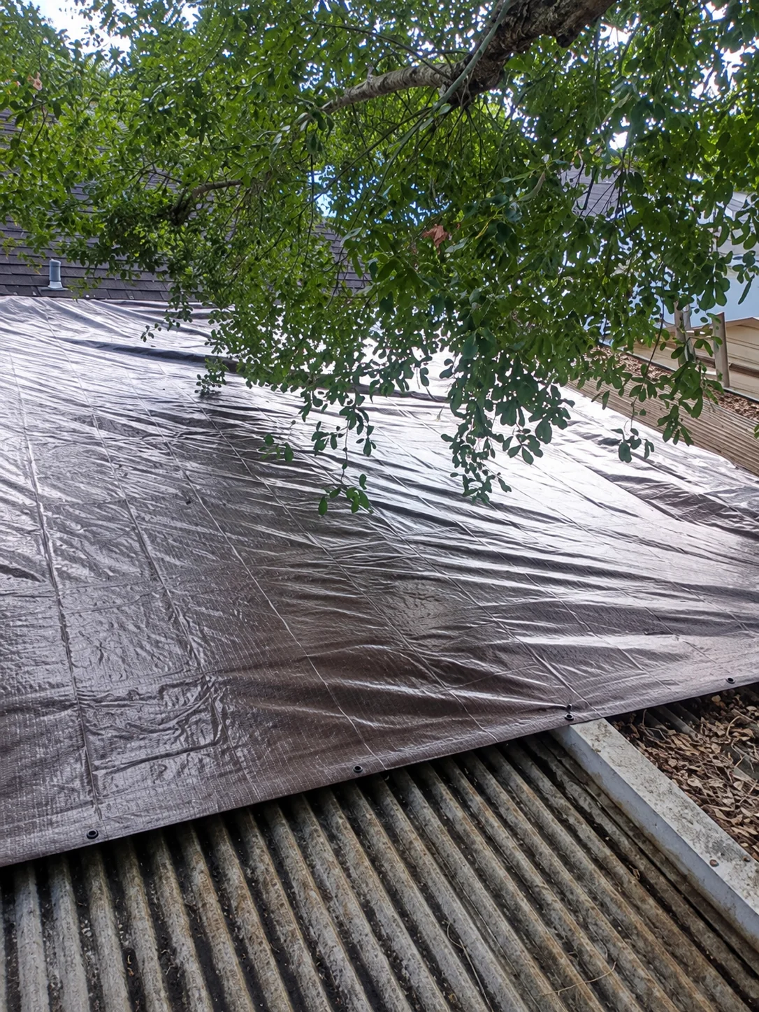 Temporary roof tarp secured over a damaged roof area